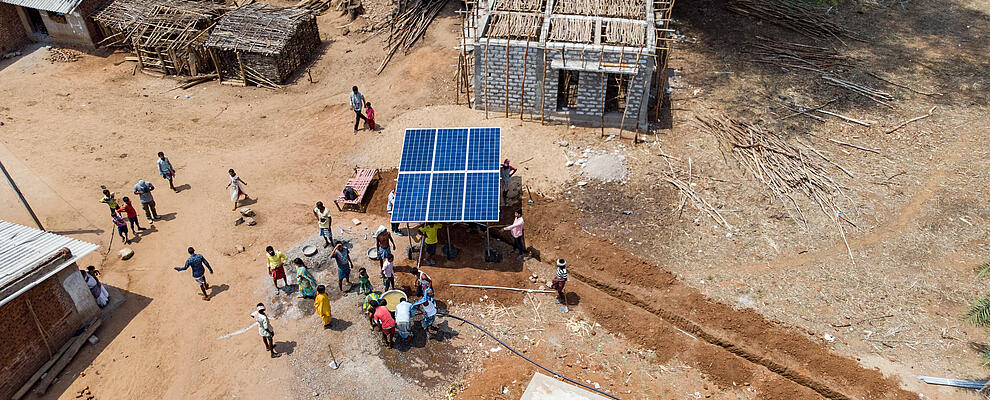 Luftaufnahme eines afrikanischen Dorfes, in der Mitte eine Solaranlage