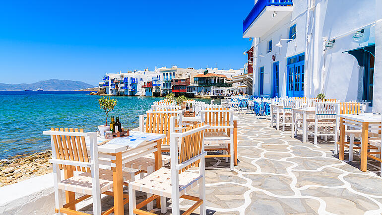 Chairs with tables in typical Greek tavern in Little Venice part of Mykonos town, Mykonos island, Greece