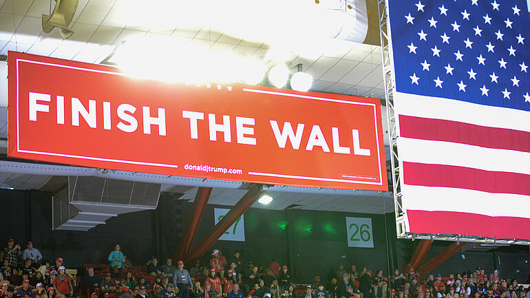 Trump election event with banner saying "Finish the wall"