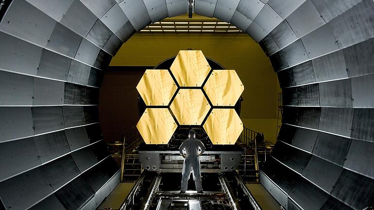 Man standing in front of large space telescope 