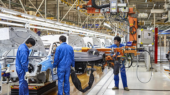 Arbeiter, die Autos auf der Montagelinie von Shanghai Volkswagen installieren und installieren, sind beschäftigt / Workers who install and install cars on the Shanghai Volkswagen factory assembly line are busy