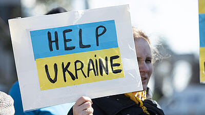 Woman holds up sign with words "Help Ukraine"