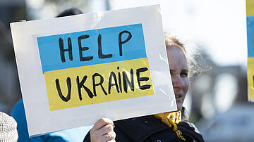 Sign hold up by a woman saying "Help Ukraine"