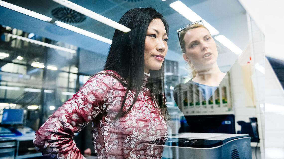 Two women seen through a window discussing something