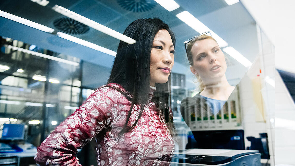 Two women seen through a window discussing something