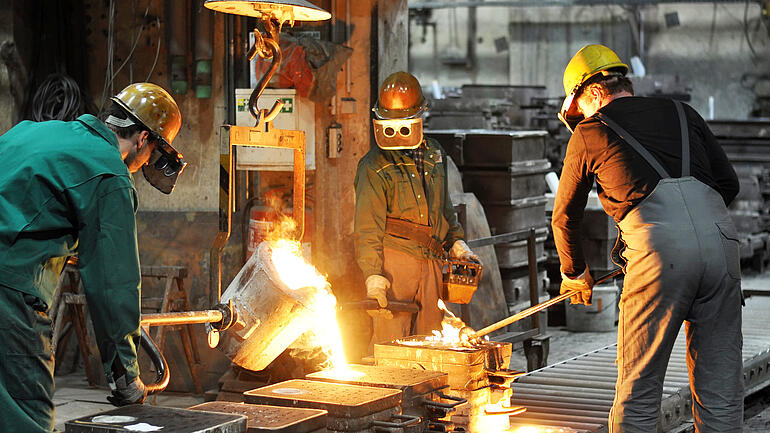 Gruppe von Arbeitern in einer Gießerei bei dem Schmelzofen / Group of workers in a foundry at the melting furnace