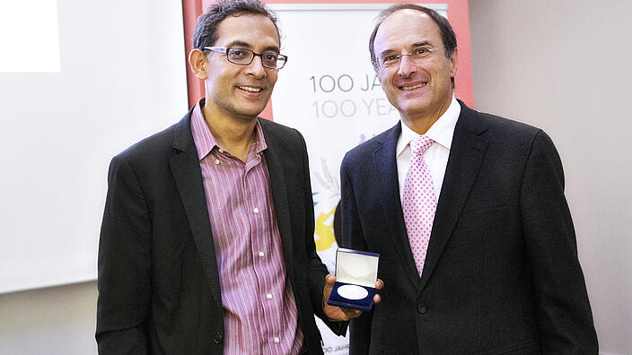 Abhijit Banerjee and Dennis Snower smiling and showing the medal Banerjee received at the Bernhard Harms Prize ceremony.
