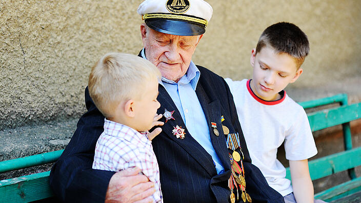 WWII veteran with children. Grandchildren looking at grandfather