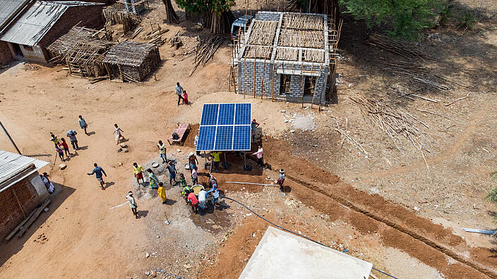 Luftaufnahme eines afrikanischen Dorfes, in der Mitte eine Solaranlage