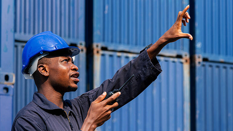 black african american man worker working control loading freight containers at commercial shipping dock