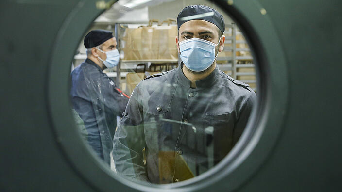 View into a kitchen with chefs wearing masks